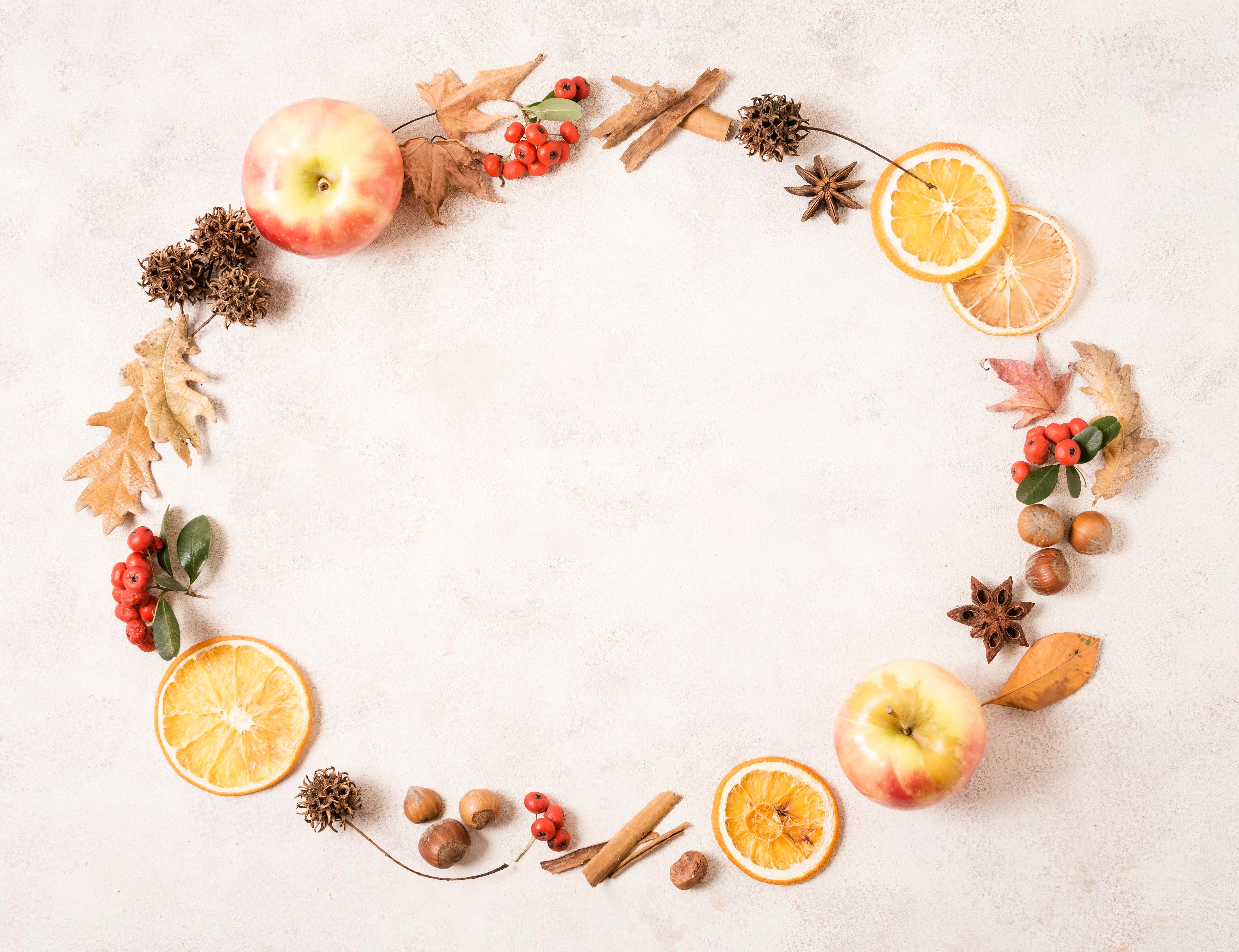 Decorative wreath made of apples, oranges, and spices on a light background
